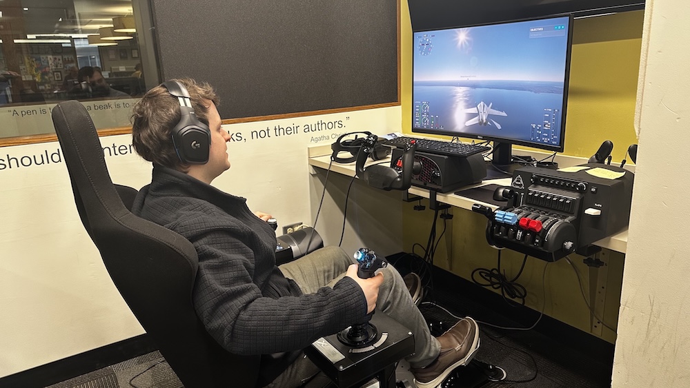 man sitting in chair with flight controls and digital display